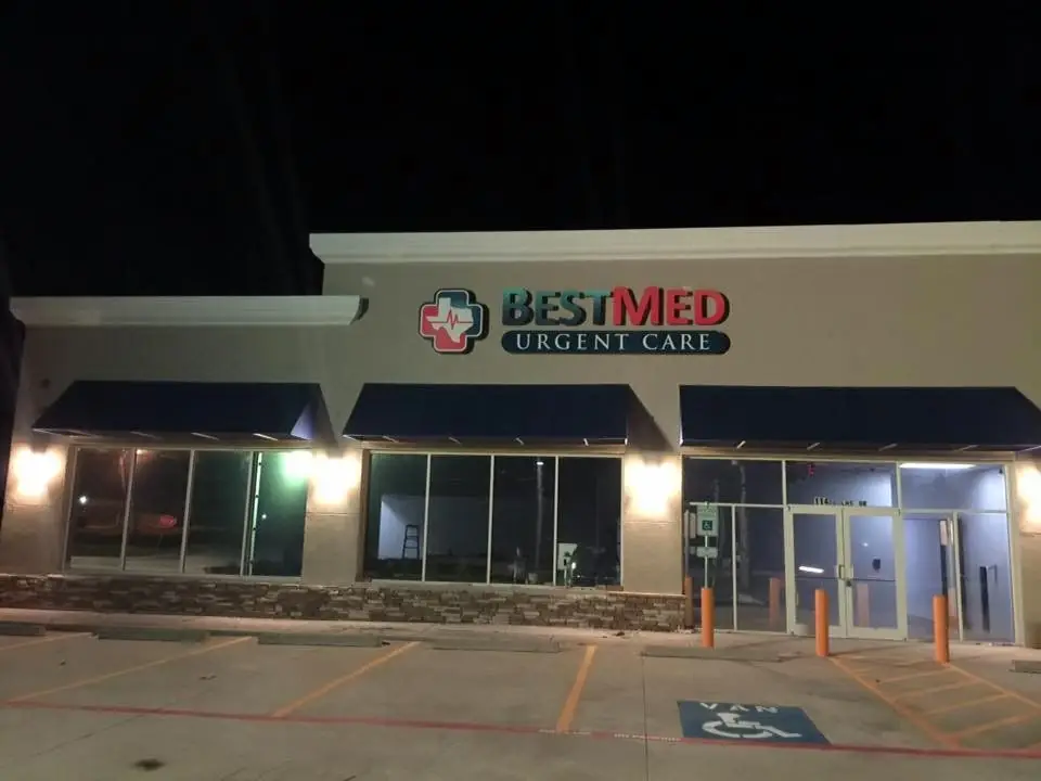 A single storey clinic building at night with lit signage and canopy lighting