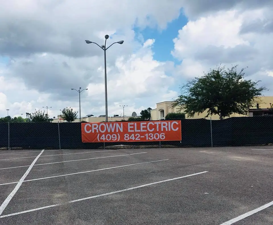 Crown Electric banner reading Crown Electric 409-842-1306 fixed to the site fence at a Beaumont job