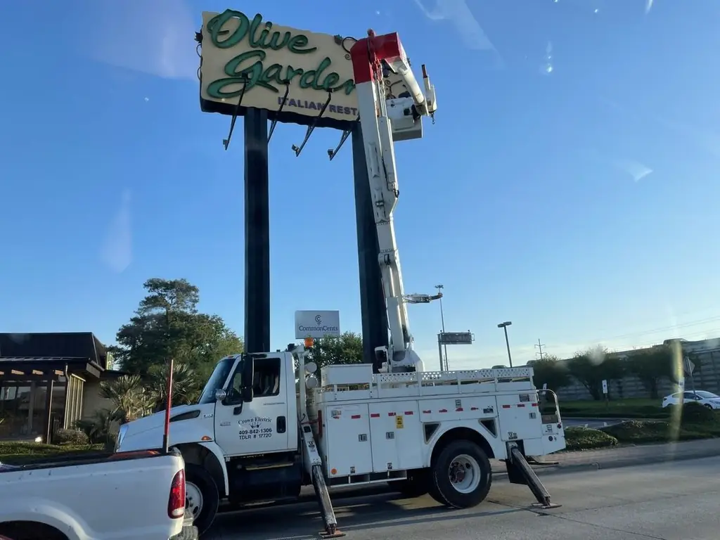 Crown Electric bucket truck with its boom extended to a raised commercial sign pylon