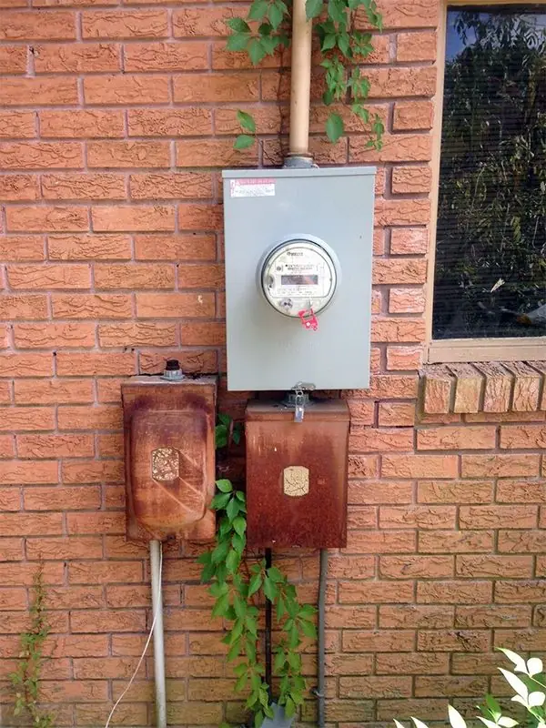 An old rusted service panel on a house exterior, the condition that a Crown Electric heavy-up replaces